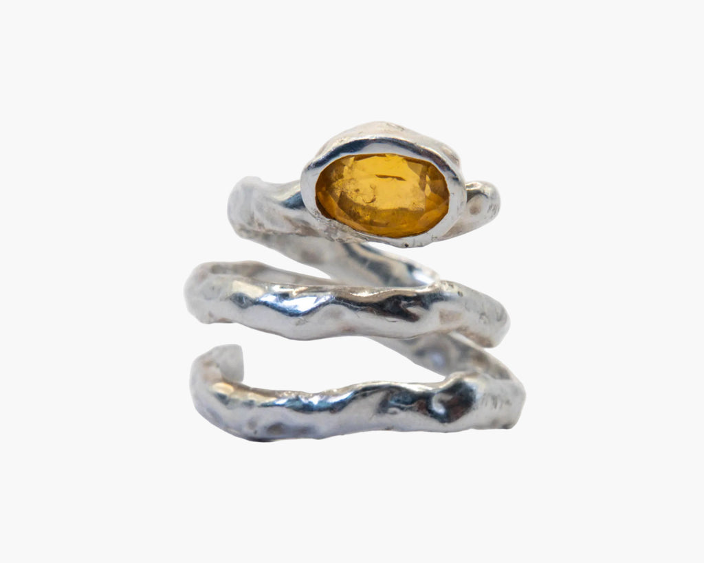 Silver ring with a yellow gemstone on a white background