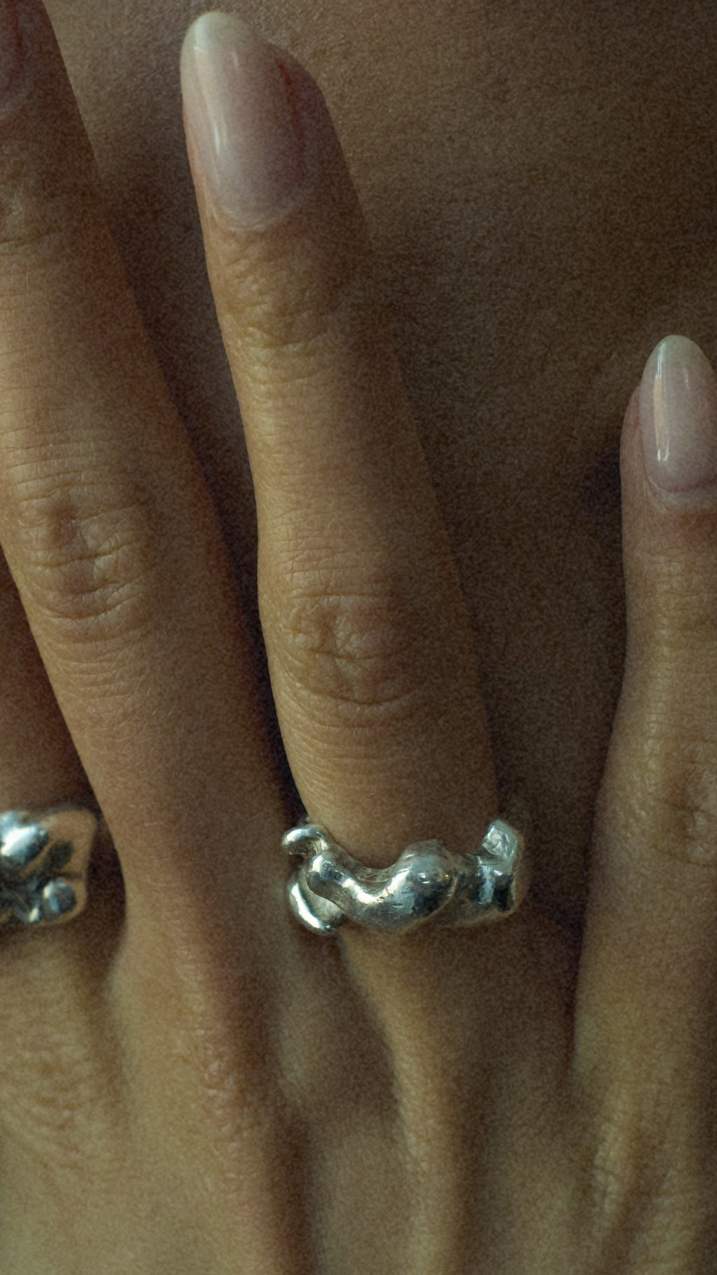Close-up of a hand with two silver rings on a blurred background