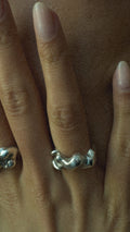 Close-up of a hand with two silver rings on a blurred background