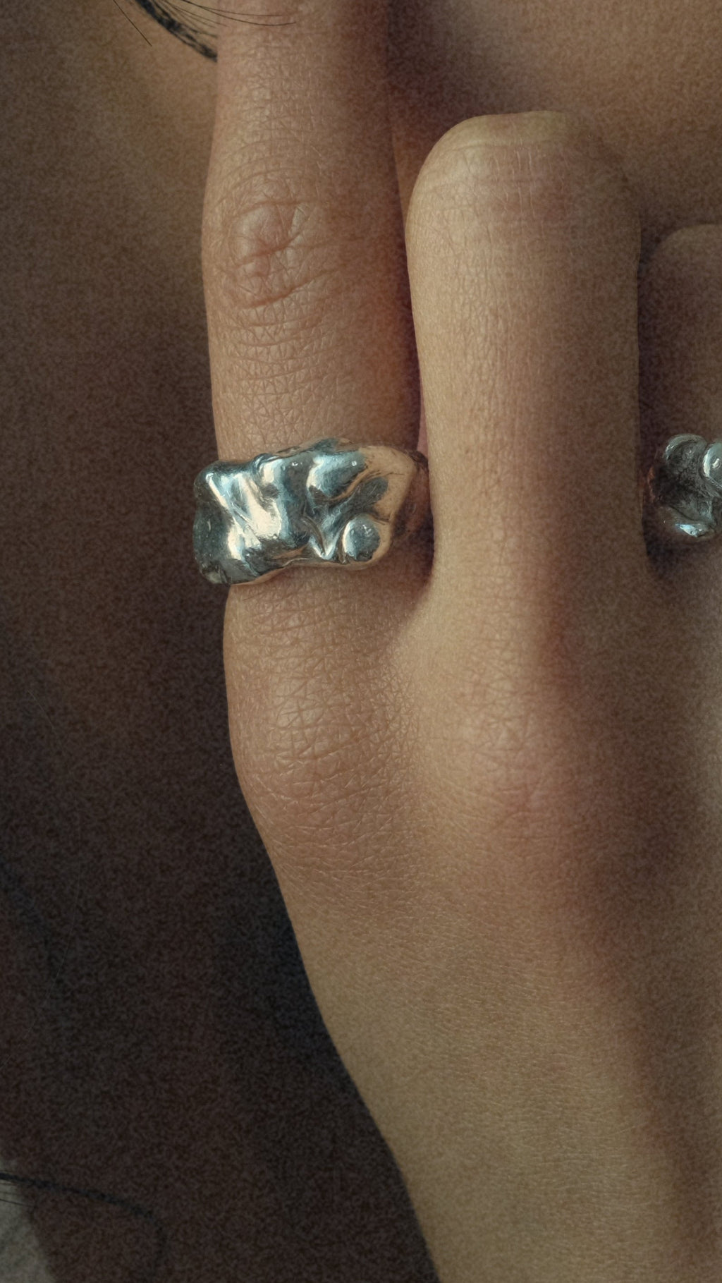 Close-up of a person wearing a silver bow-shaped ring on their finger.