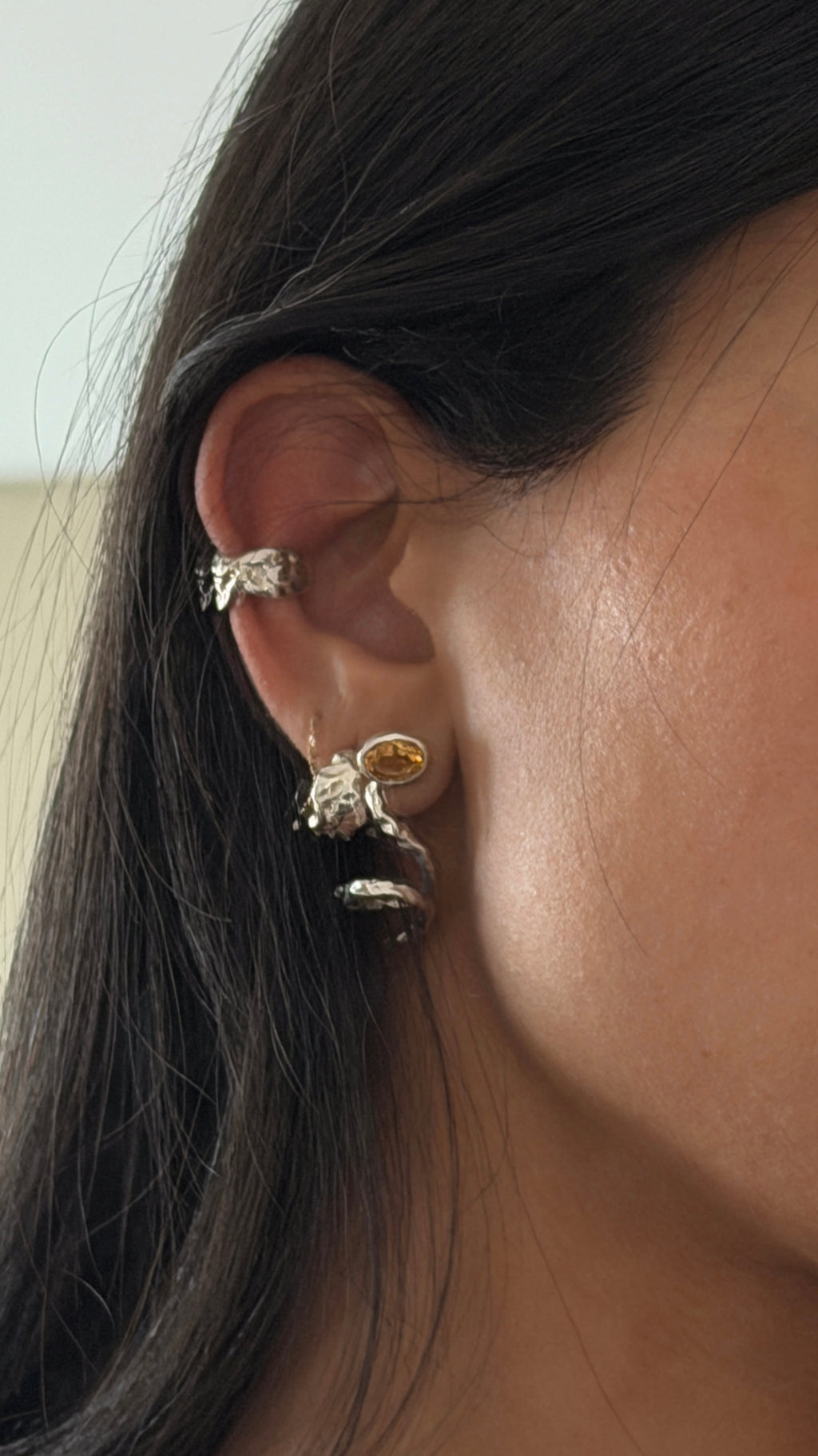 Close-up of an ear with a silver earring and ring, hair partially visible.